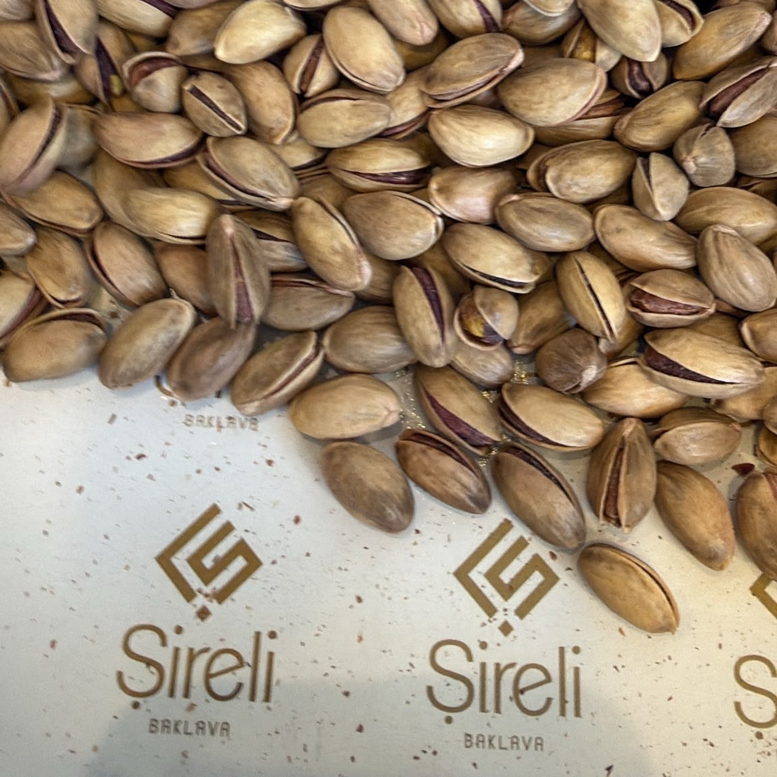 Şireli Baklava logolu zeminde kavrulmuş Antep fıstığı